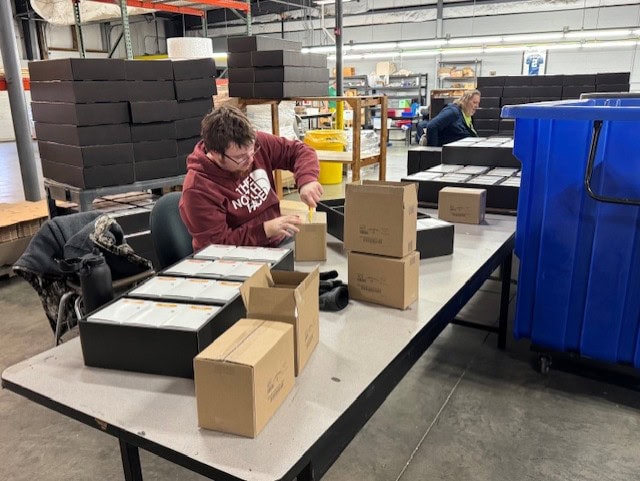 Man sitting at a table with boxes and products packing them