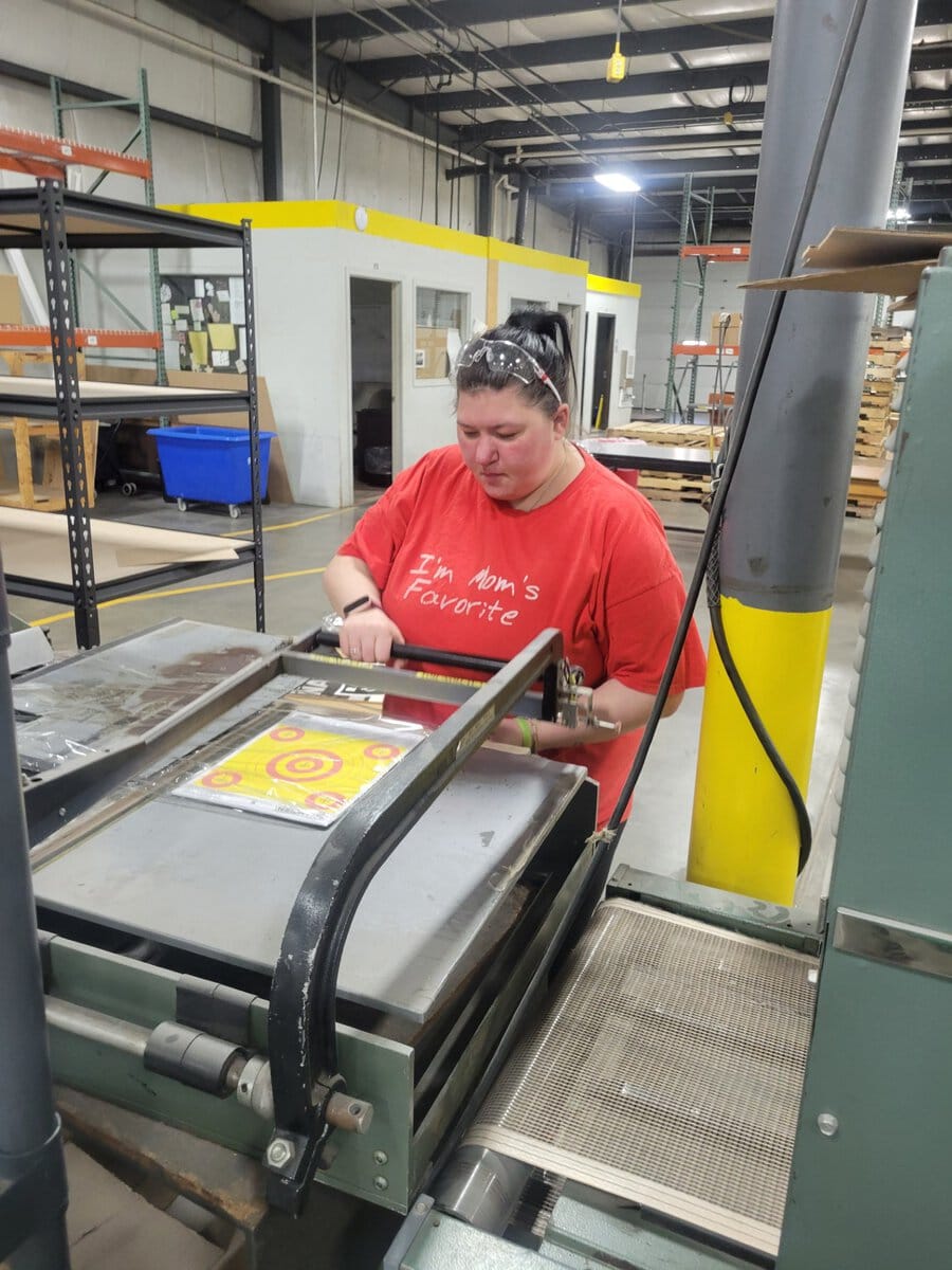 Woman running a bullseye package through the heat sealer