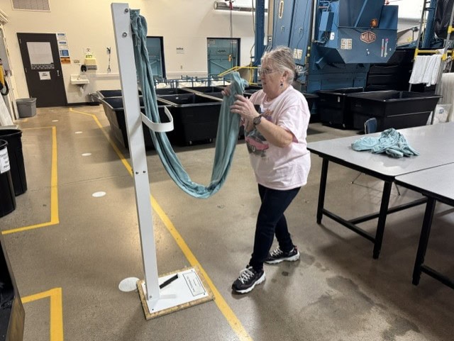 Woman using a folding arm to fold a sheet.