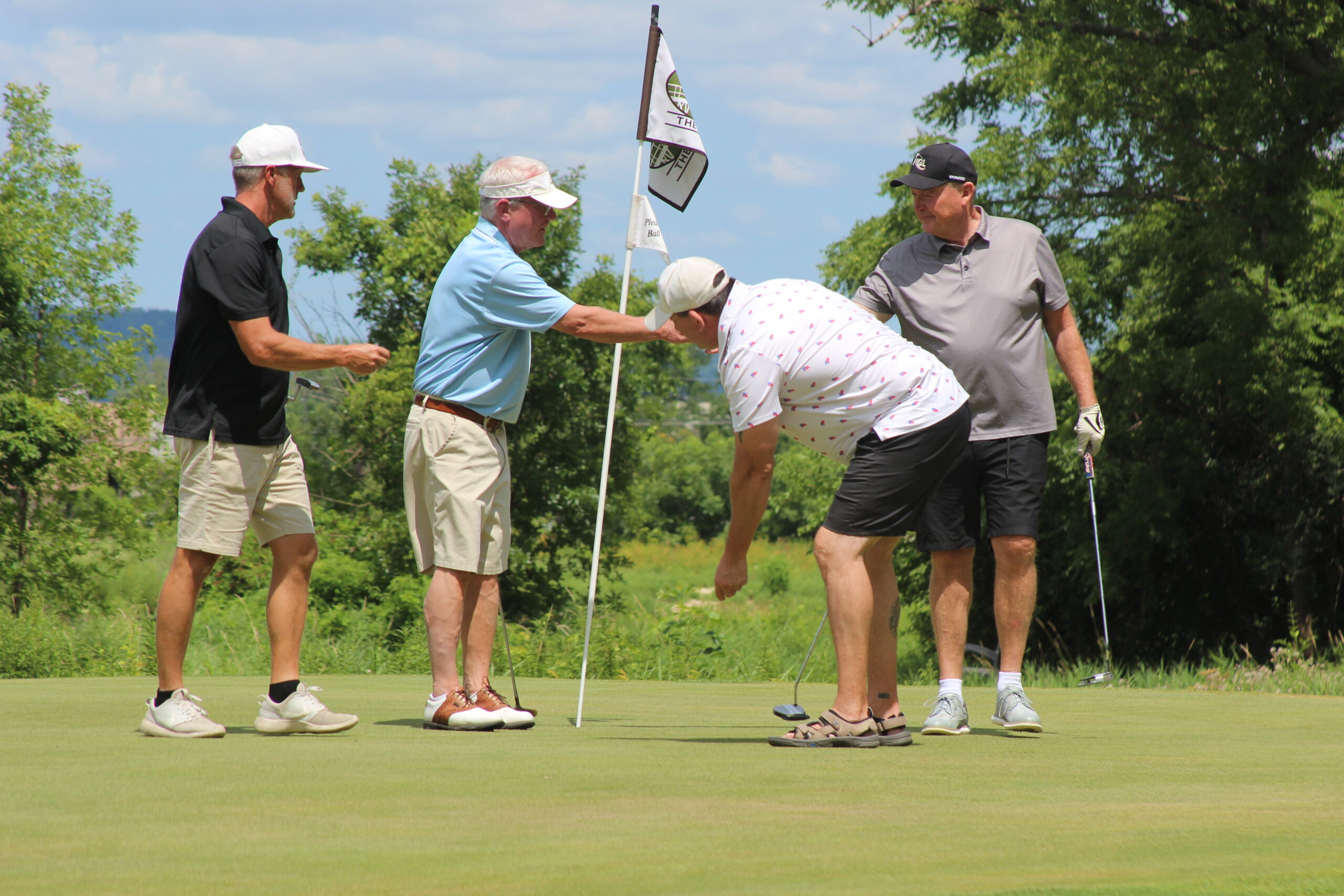 Media2 4 men golfing putting flag back in cup