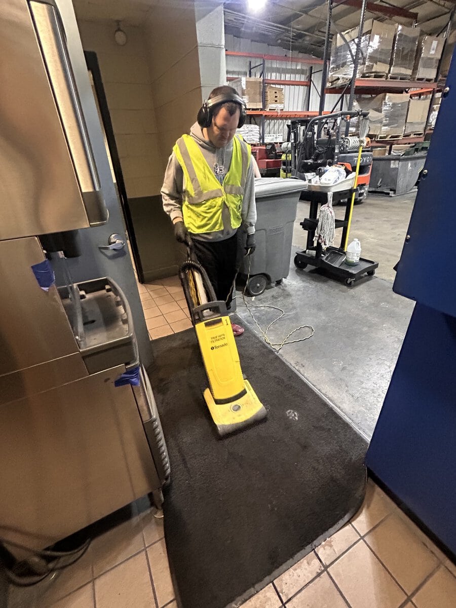 Man with headphones vacuuming a mat at RTP
